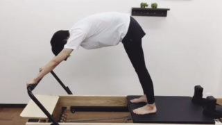 ピラティスリフォーマーでベアラウンドをする女性
