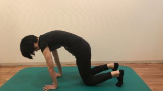 四つ這い姿勢で背骨を丸める女性