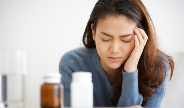 頭痛薬を飲む女性